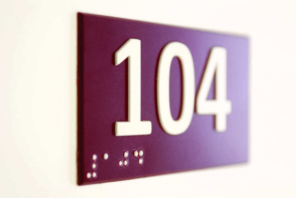 Une plaque de porte avec numéro en braille et en relief