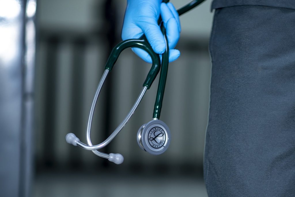 Image d'un stéthoscope tenu dans une main d'un personnel soignant avec un gant bleu