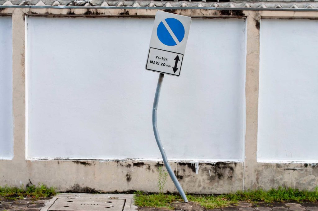 Poteau de signalisation embouti par une voiture sur un parking 